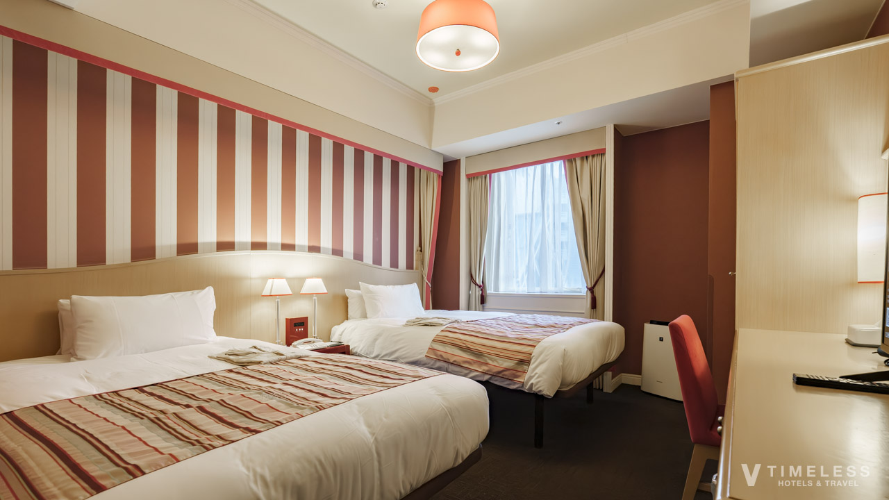 ホテルモントレ京都のスタンダードツイン客室|赤を基調にしたクラシカルな内装と2台のベッドが並ぶ落ち着いた部屋