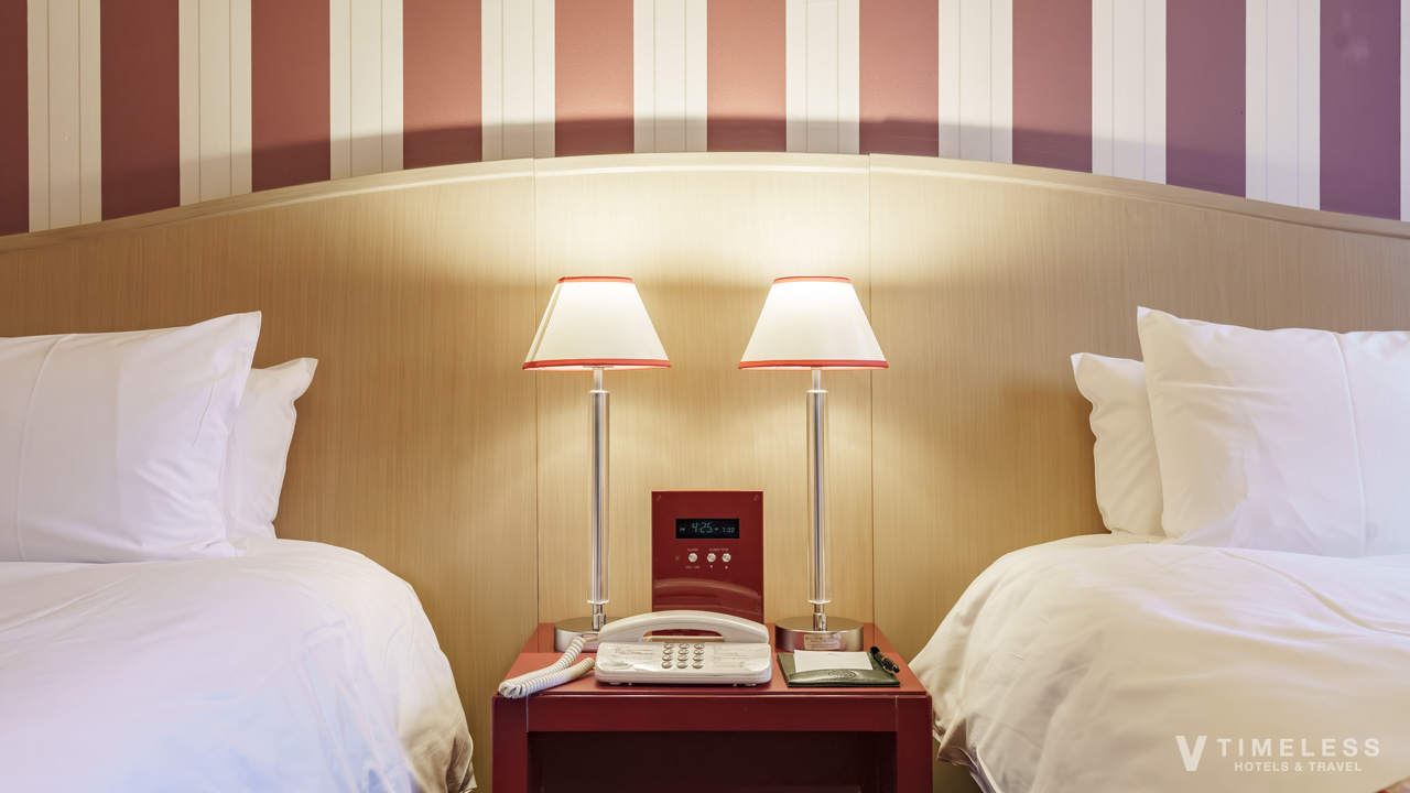 ホテルモントレ京都 客室のベッドサイド|スタンダードツインの2台ベッドと間接照明が印象的なクラシック空間