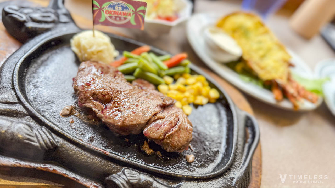 88ステーキ 国際通りの食卓風景｜鉄板ステーキと付け合わせ、背景にシーフード系の一皿が並ぶ