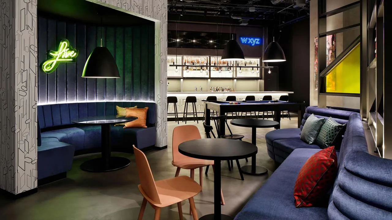 ネオンサインやビリヤード台が写真映えするアロフト大阪堂島のバー。深いブルーのソファに身を沈め、カクテル片手に語り合う大人の夜