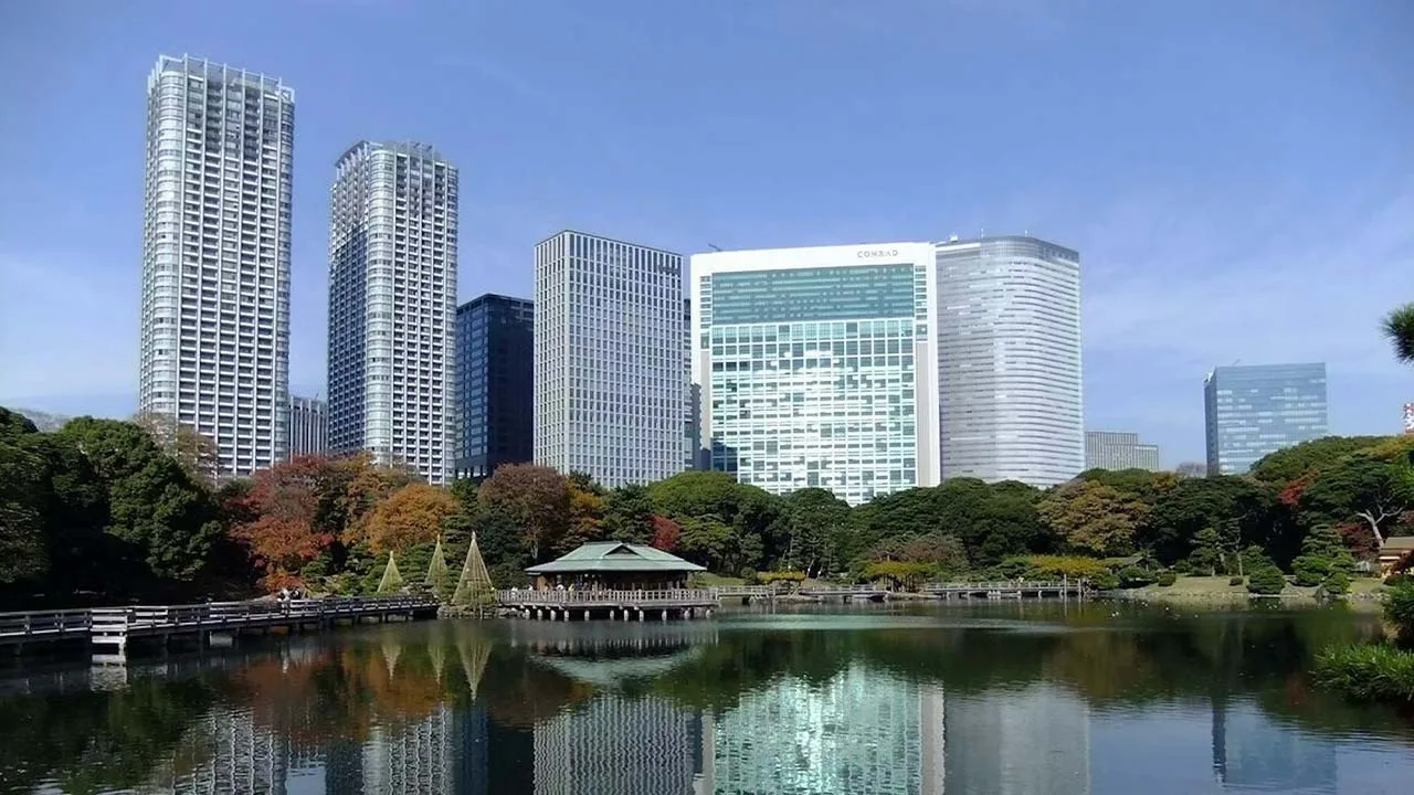 秋の浜離宮恩賜庭園の風景と背後にそびえ立つコンラッド東京の外観