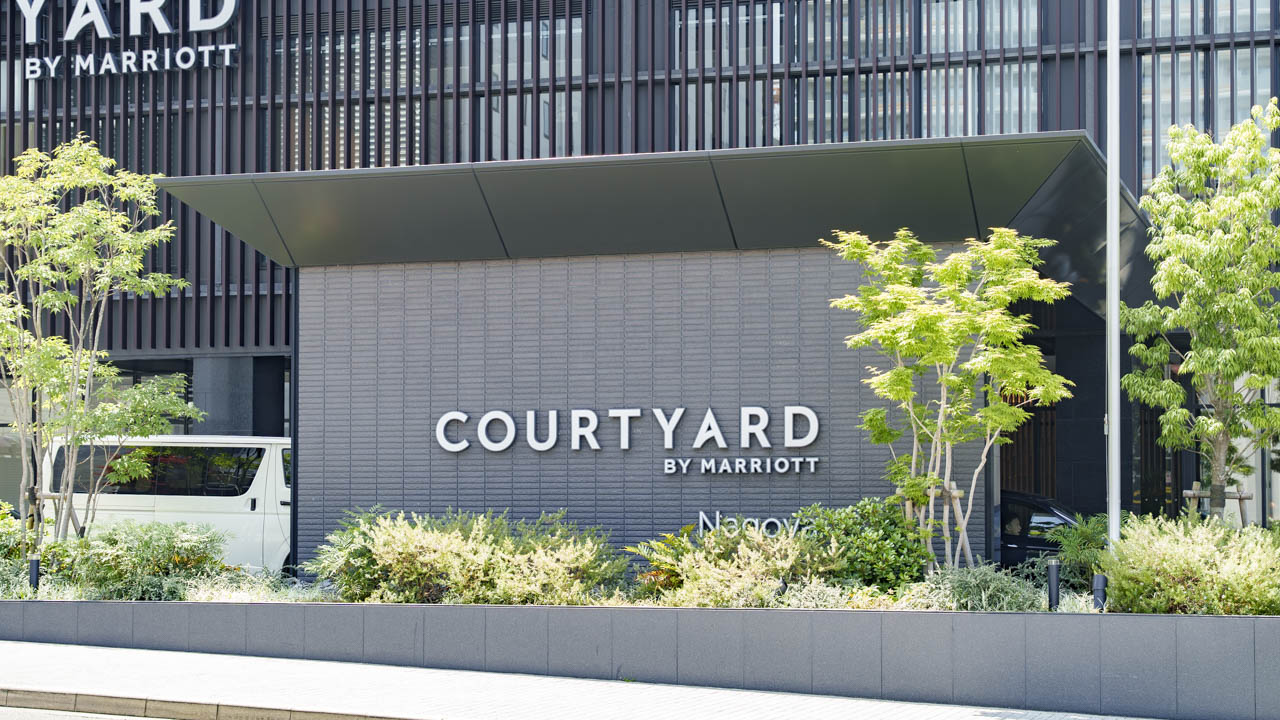 緑の植栽に囲まれたエントランスのCOURTYARDサイン