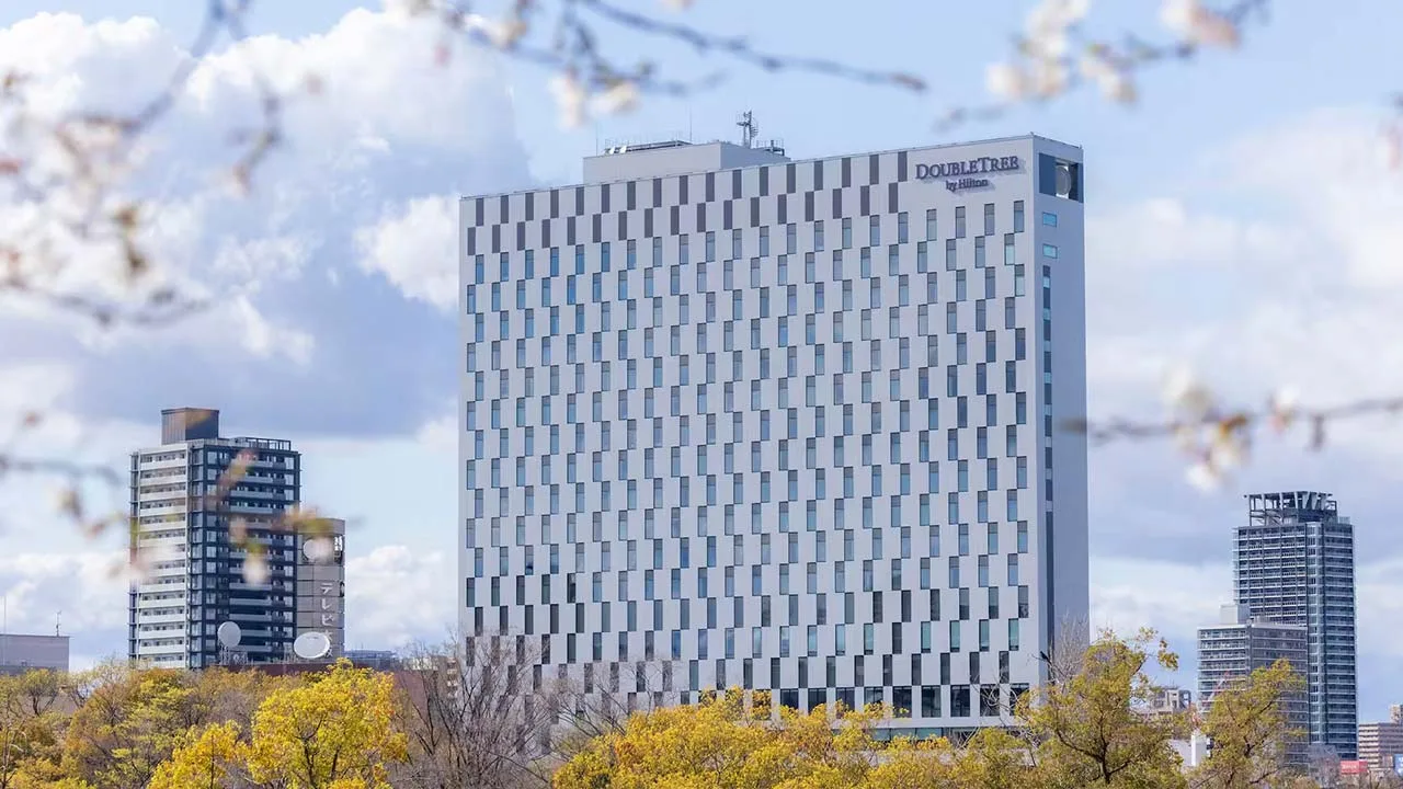青空の下にそびえ立つダブルツリーbyヒルトン大阪城のモダンなホテル外観