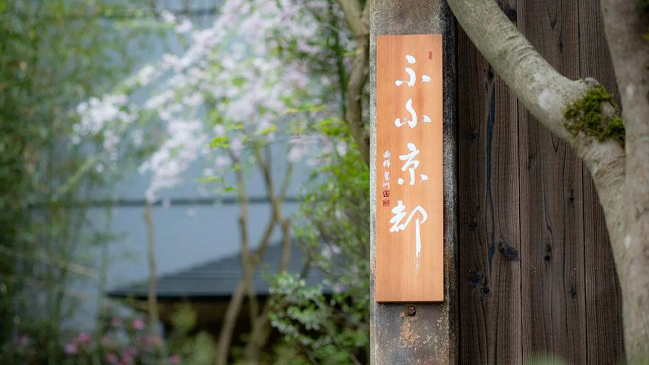 柔らかな桜の景色に溶け込むふふ 京都の美しい木の看板、ここから始まる特別な休日への期待感