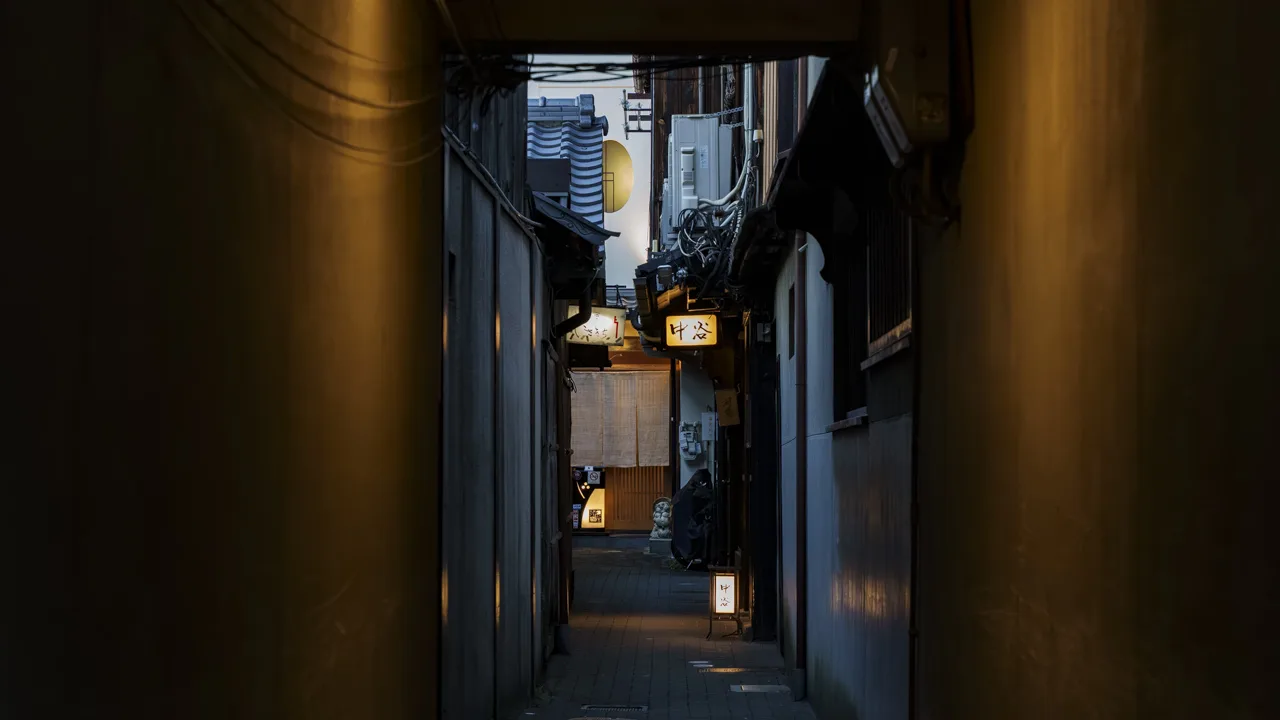 路地の奥で看板の灯りが待つ、日暮れの祇園