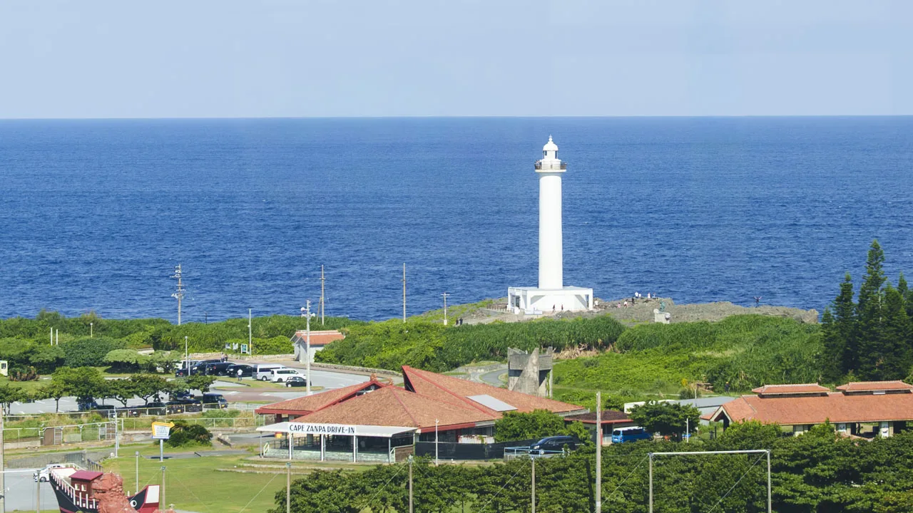 沖縄の風を感じる赤瓦の屋根と、コバルトブルーの海に浮かぶようにそびえる残波岬の灯台。ノスタルジックで美しい眺め