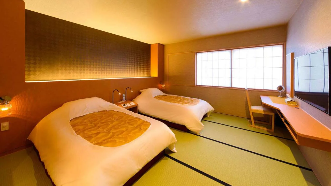 畳に寝心地の良いローベッドを配した和モダンな料理旅館 金沢茶屋の寝室。温かみのある間接照明が心地よい眠りを誘うリラックス空間。
