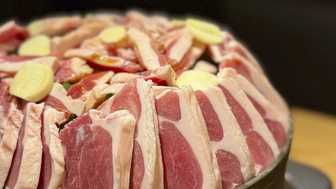 鉄鍋いっぱいに立てかけるように盛られた鴨肉