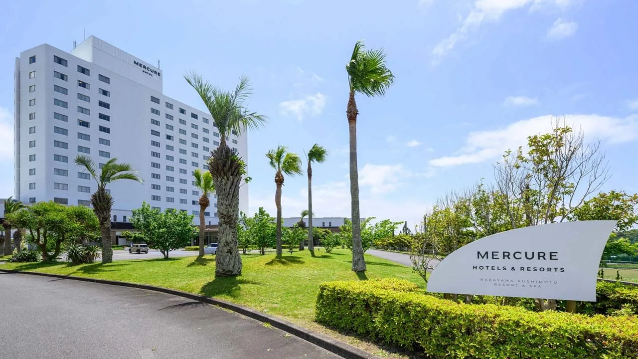 抜けるような青空とヤシの木に迎えられるメルキュール和歌山串本リゾート&スパの外観。ここから始まる非日常のリゾートステイへの期待が高まるエントランス。