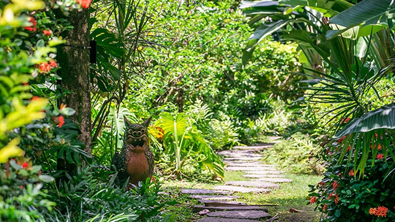 沖縄ハーバービューホテルの緑豊かなガーデン。南国の植物に囲まれた石畳の小道と、ひっそりと佇むシーサーが迎える癒しの風景。