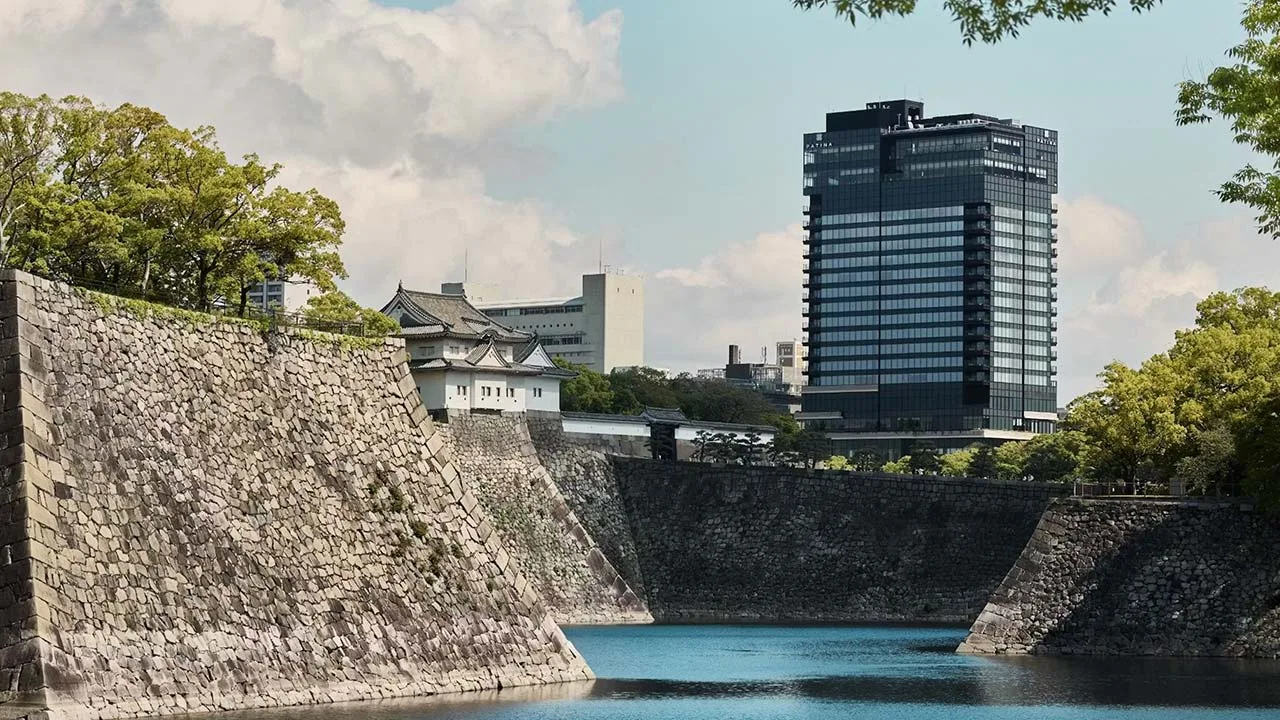 大阪城の美しい石垣と堀の奥にそびえ立つパティーナ大阪の外観