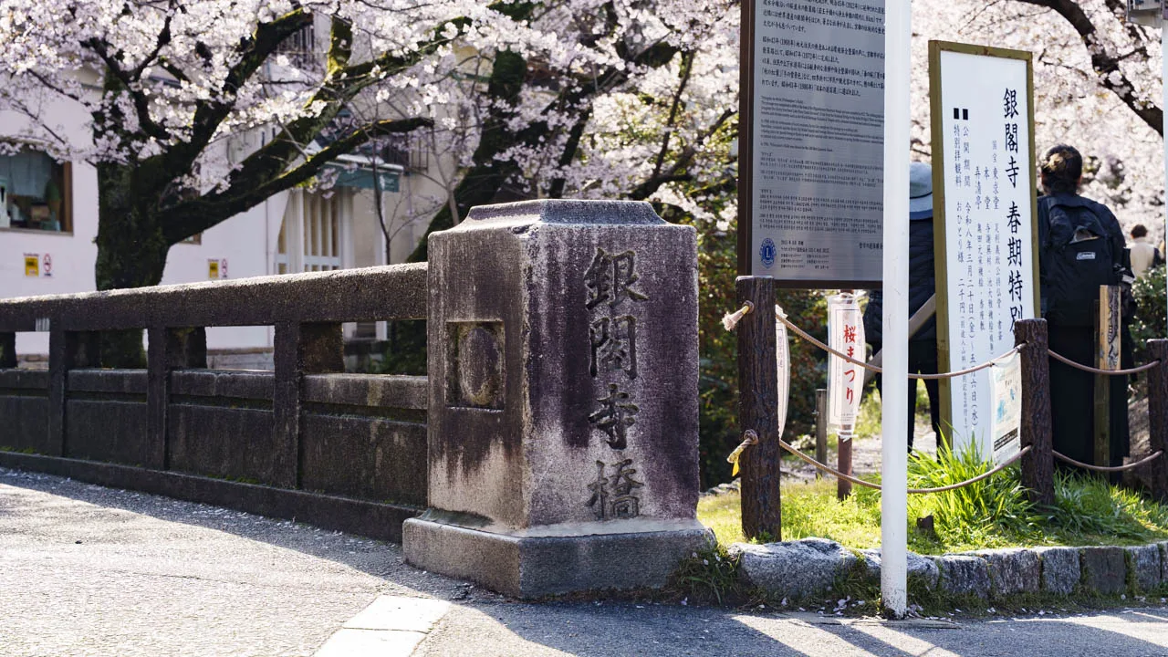 「銀閣寺橋」と刻まれた石の親柱と桜