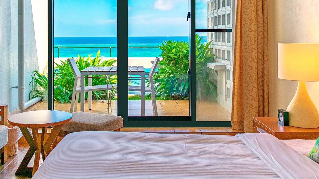 大きな窓から美しい海と空を一望できるザ・ムーンビーチ ミュージアムリゾートの客室。ふかふかのベッドでくつろぎながら絶景を独り占めする至福のプライベートステイ